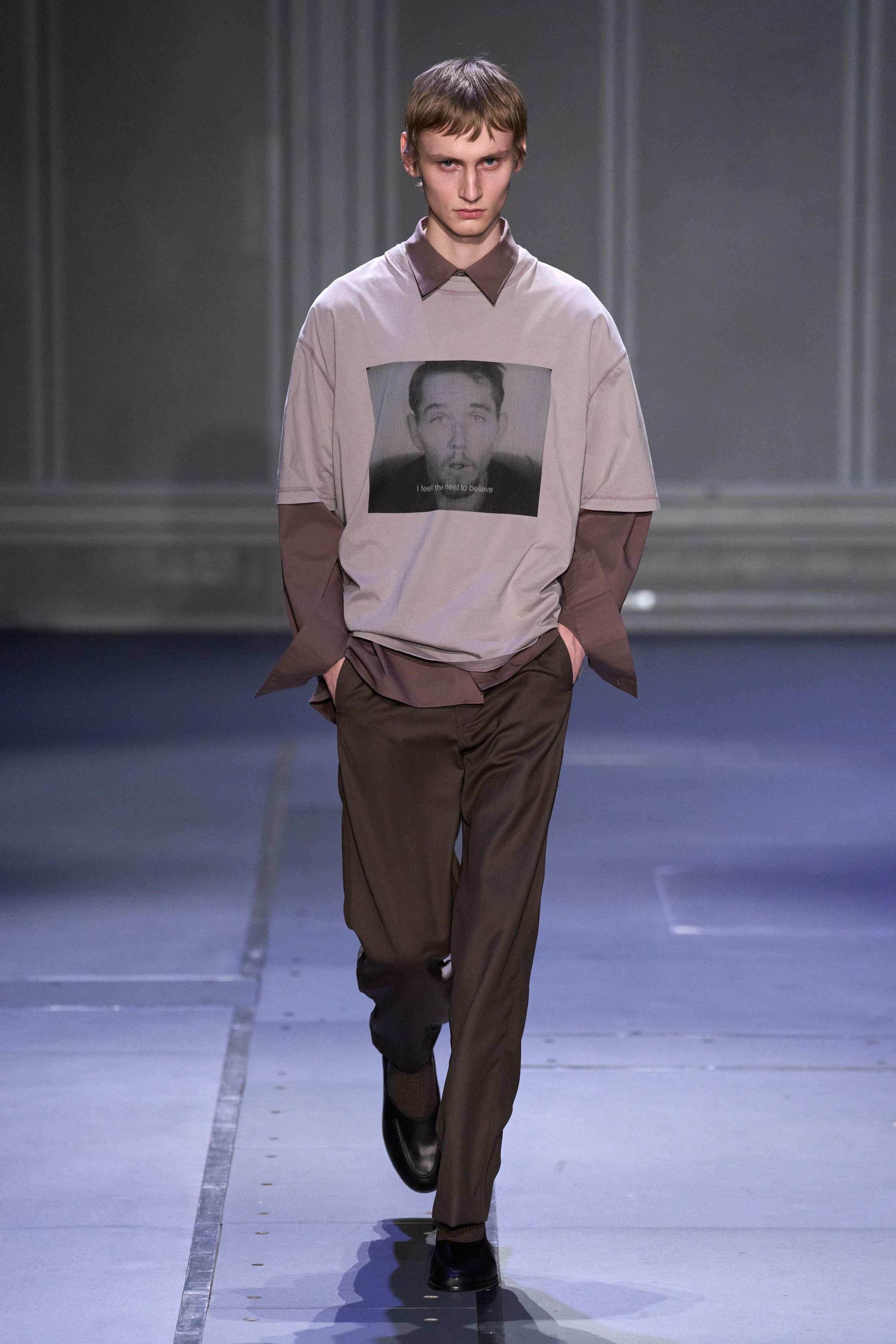 Études Studio 26FW 延续其标志性的“巴黎青年智识气质”，在克制的灰、棕、墨绿与深紫中，将街头轮廓与艺术语境并置。摄影肖像印花、皮革长风衣、渐变针织与蓬松羽绒共同构建出一种略带疏离感的城市诗意。系列并不追求强烈戏剧冲突，而是通过材质反差与比例控制，呈现介于学院派、亚文化与当代艺术之间的中间地带，体现 Études 一贯的文化策展式设计方法美-顽石频道趋势研究